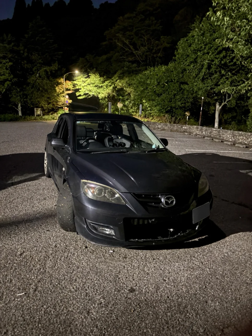 夜の駐車場でマツダスピードアクセラを斜め前から撮影した写真をもとに、AIでナンバーを匿名化した掲載用画像